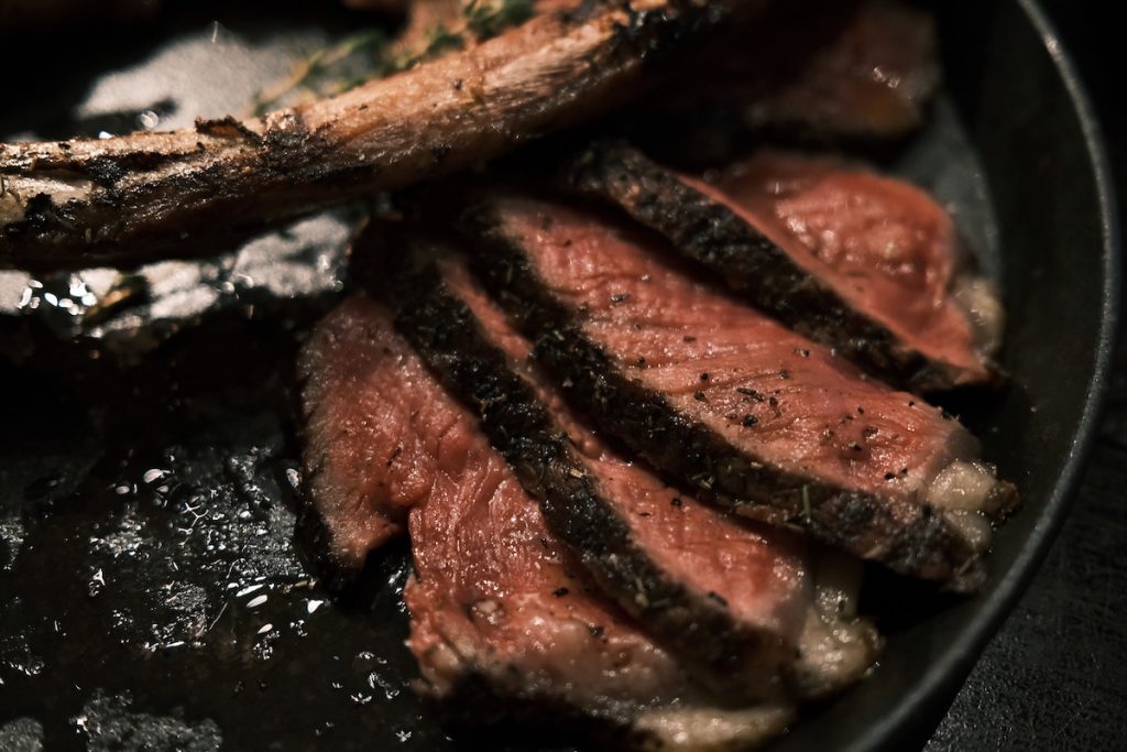 A cut cooked steak sitting on a restaurant plate