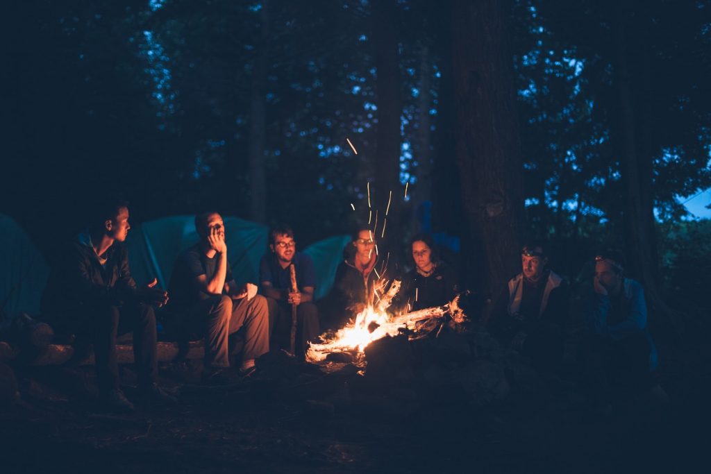 Group of friends sitting around a campfire at a camp site