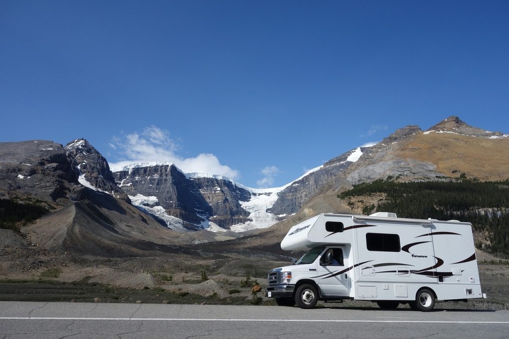 motorhome driving down a scenic road with mountains in the background
